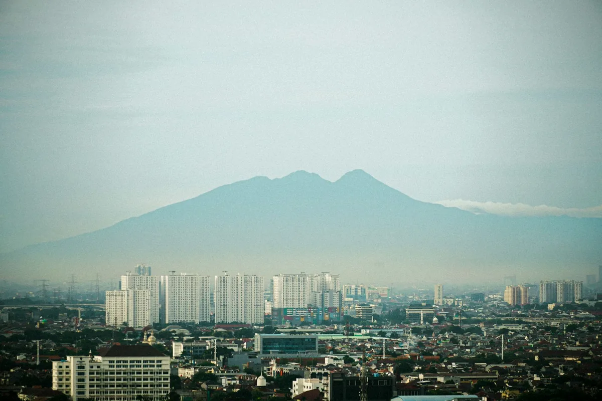 Kota berlatar siluet gunung di pagi hari, area layanan Bogor